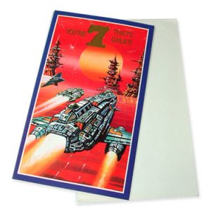 Image shows a 1980's birthday card with a bright red background and a space-age illustration of a space craft flying towards an alien city. Text reads: You're 7 That's Great!