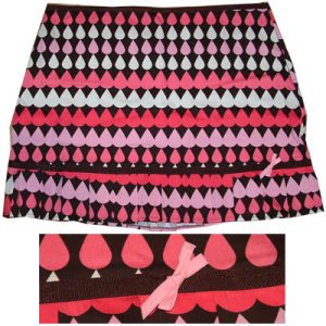 Image shows a short, frilled skirt adorned with bow, with a pattern of linear teardrops in rows of white and pink